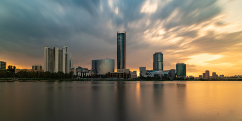 Beautiful cloudy sunset at the city pond. Long Exposure cityscape of Yekaterinburg, Russia with skyscrappers reflecting in water