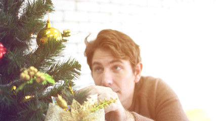 Caucasian man excited decorating Christmas tree and waiting to surprise family