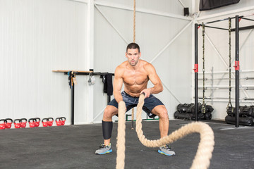 Naklejka na ściany i meble Men with battle ropes exercise in the fitness gym