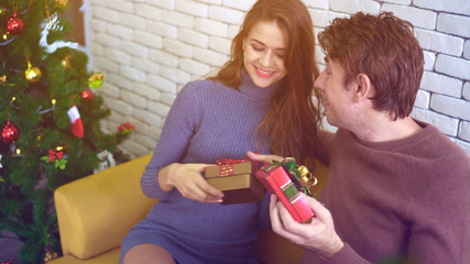 Happy Caucasian couple exchange gifts on Christmas day