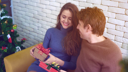 Happy Caucasian couple exchange gifts on Christmas day