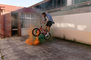 BMX rider jumping over smoke grenades
