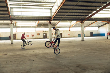 BMX riders in an empty warehouse