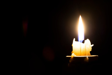 burning candle on a dark background and blurry highlights on an empty black background on the left side