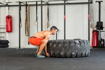 Obraz na płótnie Canvas Bodybuilder flipping tire at the gym