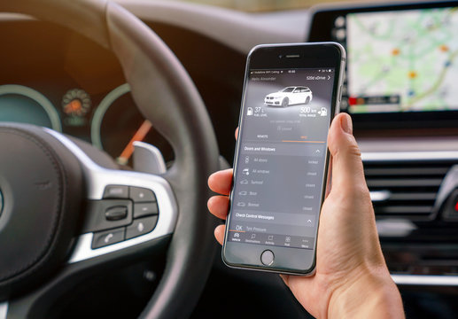 AACHEN, GERMANY AUGUST 2019: Woman Holding A Apple IPhone With BMW Smart Car App To Controll The Car