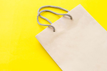Blank brown paper shopping bag on yellow background