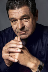 close-up portrait of an adult man in a black shirt, on a black background, studio, luxury life,...