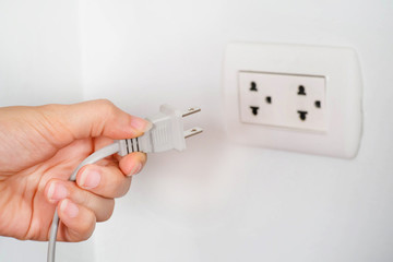 Hand holding plug with white  electric socket