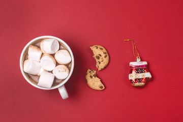 Fototapeta na wymiar White Cup of Cocoa with Marshmallow Broken Cookies and Christmas Toy in Shape of Mittens on Red Background Festive Christmas Food Backgroundor Concept Flat Lay Top View