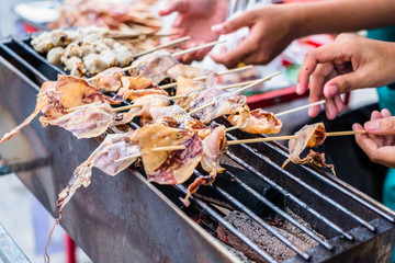 Dried squid is being grilled on stove on street in Thailand. Thai food travel and street.
