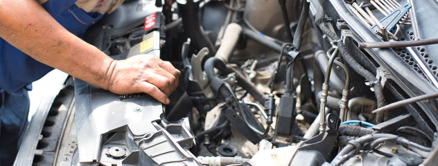 Close up of mechanic's arm placing at car engine front hood open. Auto mechanic inspecting car engine.