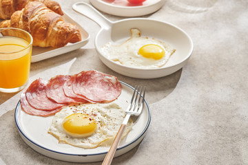 Continental breakfast. Fried eggs and sausage with croissants and orange juice.
