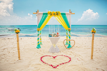 yellow and green wedding archway are arranged on the sand in preparation for a beach wedding ceremony.