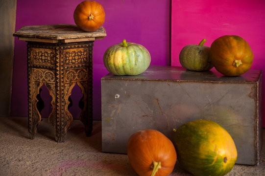 Different varieties of pumpkins on pink background in barn