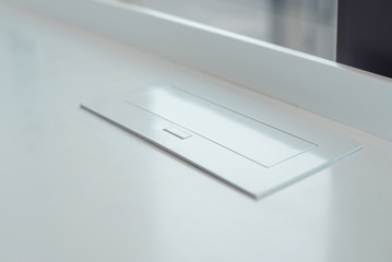 Pop up internal socket in a white table, charging for phones and devices.