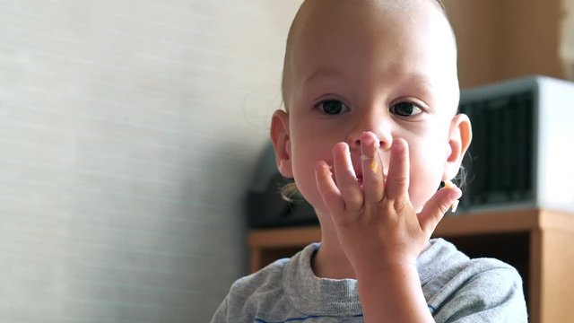 Slow motion baby boy with scratch of lips, nose and chin looks on the camera and eats. Real injury after falling out of perambulator. Video may be used for family or domestic violence
