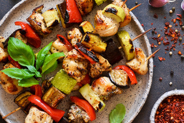 Barbecue of chicken on skewers with vegetables on stone background. Picnic.