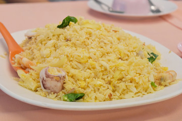 Fried Rice with vegetables and squid on plate in restaurant.