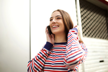 Fototapeta premium Close up smiling young woman walking and talking with mobile phone