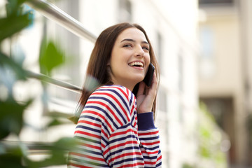 Fototapeta premium Side of happy young woman outside talking with mobile phone