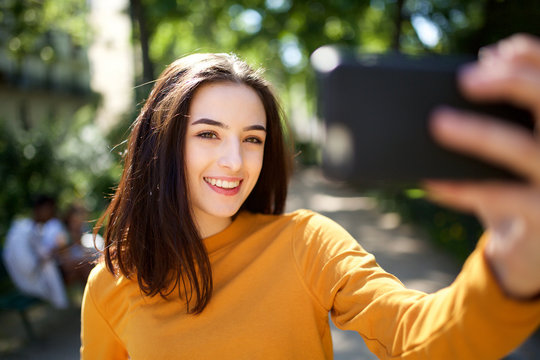 beautiful young woman taking selfie photo with mobile phone in the park