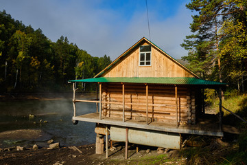 House hunting on the shore of the lake at dawn in the fog. Log home, lake mist