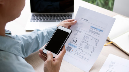 The hand uses the phone to scan the QR code to receive a discount from paying electricity bills at the office