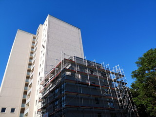 Bau von modernen Büros und Wohnungen als Hochhaus im Rohbau mit Baugerüst vor blauem Himmel im...