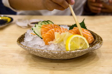 Hamachi Salmon Sashimi with shredded white radish on wooden table.