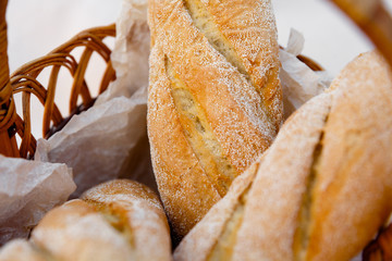 three fresh baguettes lie in a wicker basket