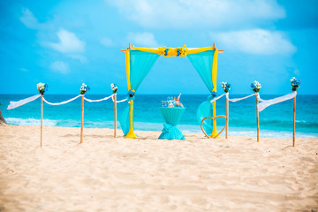 Wedding archway are arranged on the sand in preparation for a beach wedding ceremony.