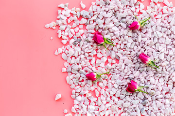Decoration with stones and flowers on pink background top view copyspace