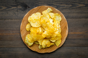 Potato chips ready to eat on wooden background top view