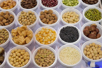 Cereal grains, seeds, beans on white plastic plate.