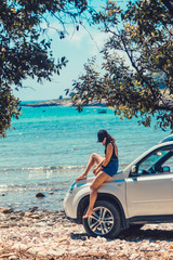 woman sitting on car hood looking on the sea beach seaside