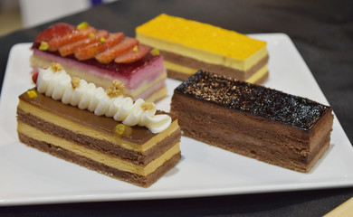Bread cakes with whipping cream, chocolate and strawberry in bakery shop glass display.