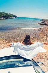 woman laying at car hood with view of sea summer beach