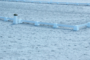 Blurred image of white arena for White fence on dressage arena. Dressage competition venue, cropped shot.