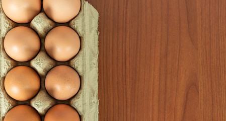 Fresh brown organic eggs in grocery package close up on wood table background