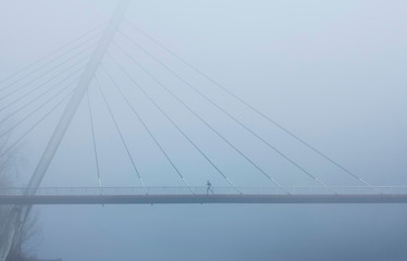 Man running over a bridge on a cold winter day