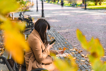 young adult fashion woman sitting at city park bench in autumn fall season