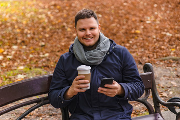 man drinking coffee outdoors autumn season talking on the phone