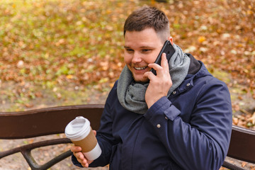 man drinking coffee outdoors autumn season talking on the phone