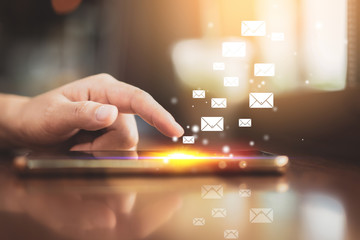 Woman hand using smart phone on old wood table texture background at coffee shop with email icon flying abstract. Technology business and freelance concept.