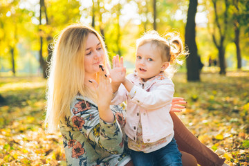 mather with little toddle daughter playing in autumn city public park
