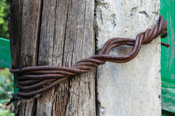 Obraz premium Background in the form of an old decrepit wooden pillar and a powerful concrete pillar interconnected by a triple thick iron wire