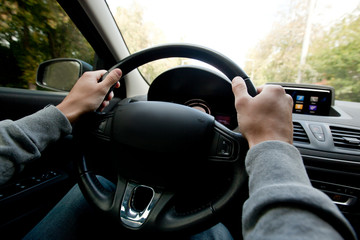 The young man driving the modern car on asphalt road