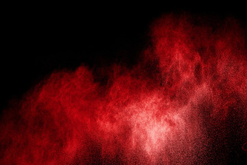 Red particles explosion on black background. Freeze motion of red dust splash on dark background.