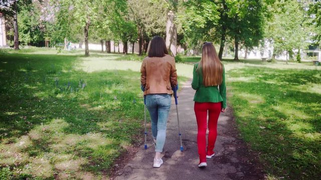 Healthy woman and friend with broken leg having a walk together